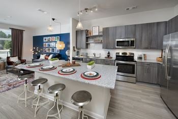 A kitchen with a large island with a breakfast bar and stainless steel appliances